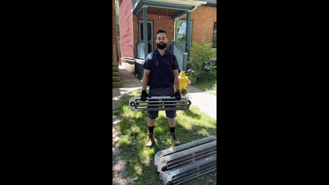 Elham Tolmal owner of Epsilon Mechanical doing bicep curls with radiator sections on a job site in Toronto