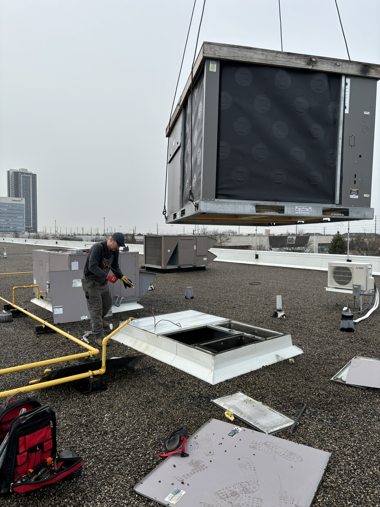 Large commercial rooftop unit being craned into position during installation by Epsilon Mechanical in Toronto