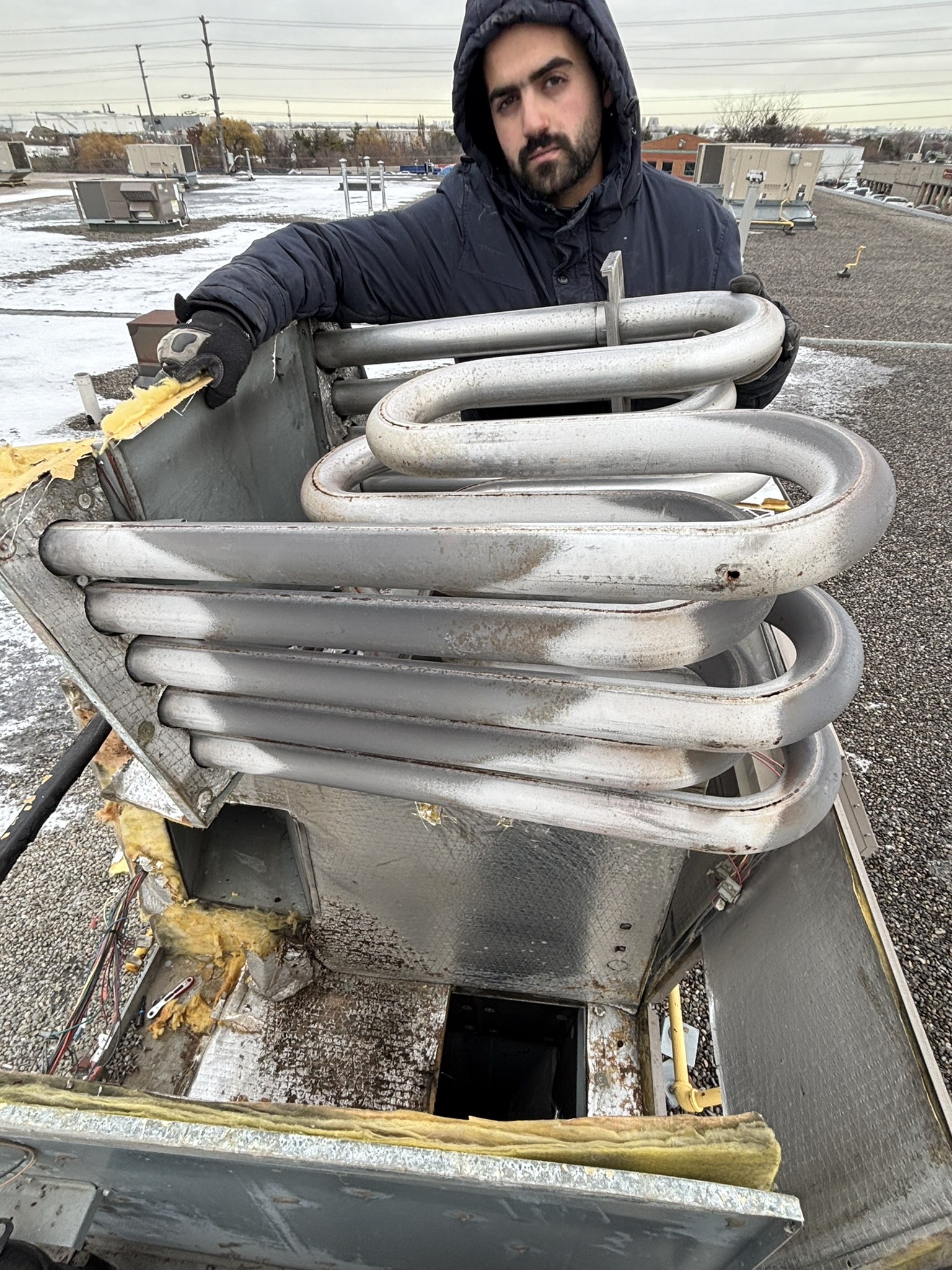 Epsilon Mechanical technician removing a heat exchanger from a rooftop RTU during commercial HVAC repair in Toronto